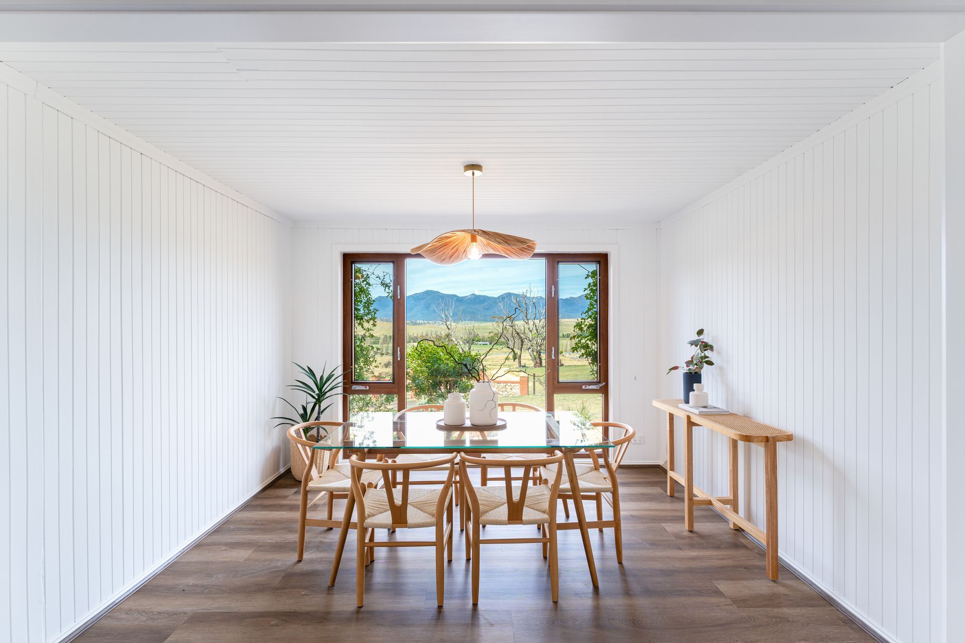 Dining room with a wooden table and chairs, large window with a view.