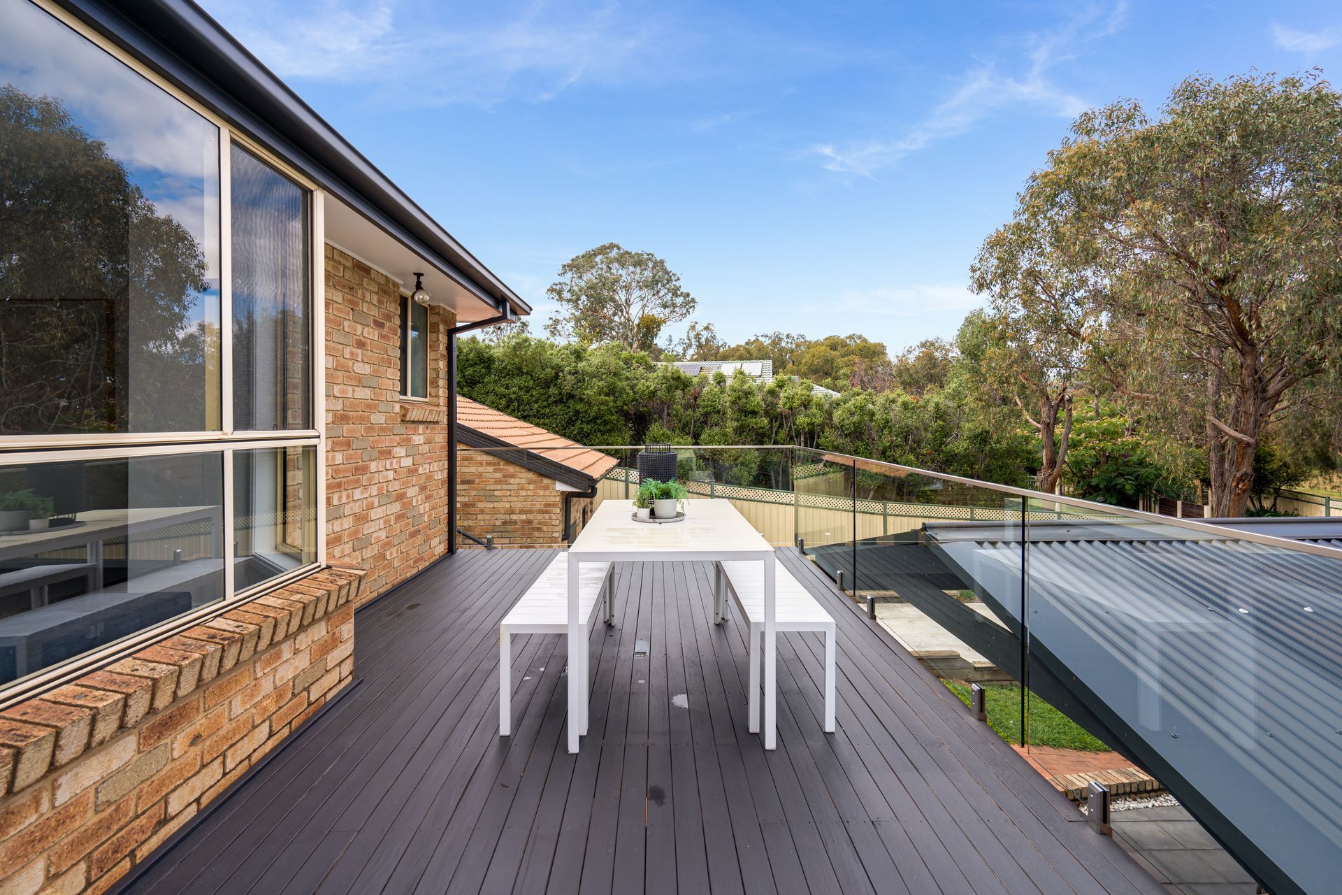 Modern kitchen with dark gray cabinets, white countertops, and wood flooring.