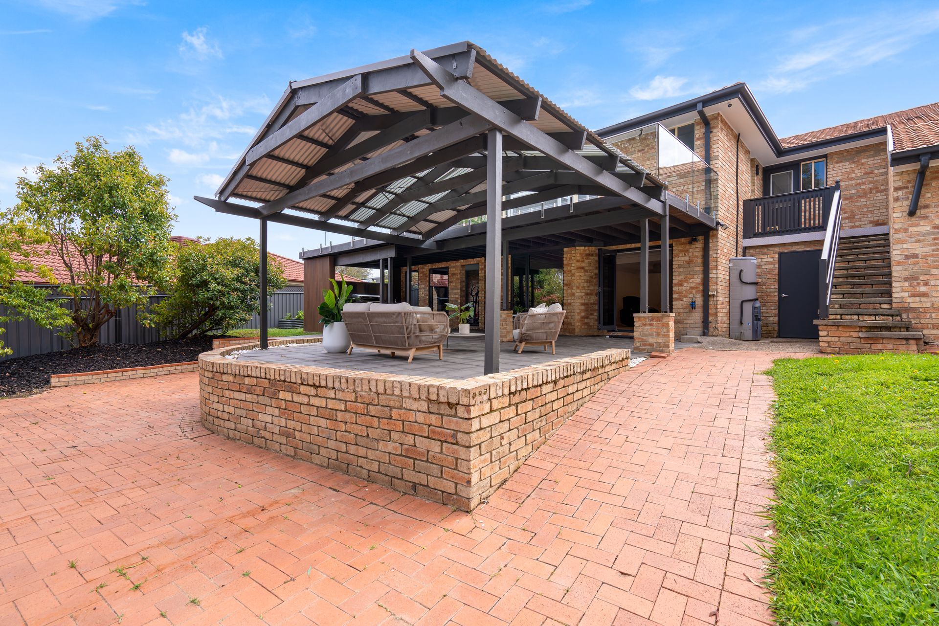 Open-plan kitchen and living area with white cabinetry, island, light wood flooring, and gray sofa.