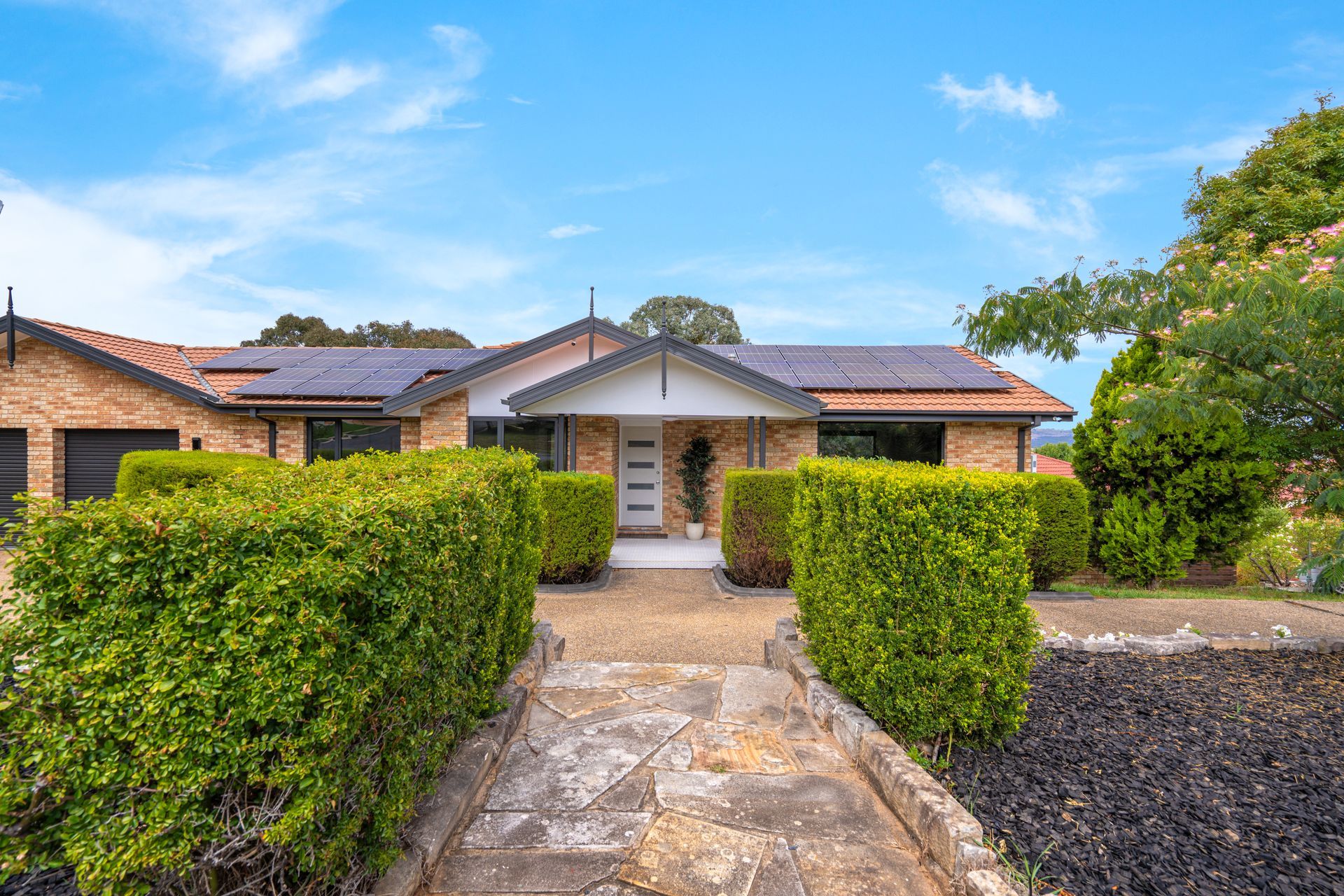 Open-plan kitchen and living area with white cabinetry, island, light wood flooring, and gray sofa.