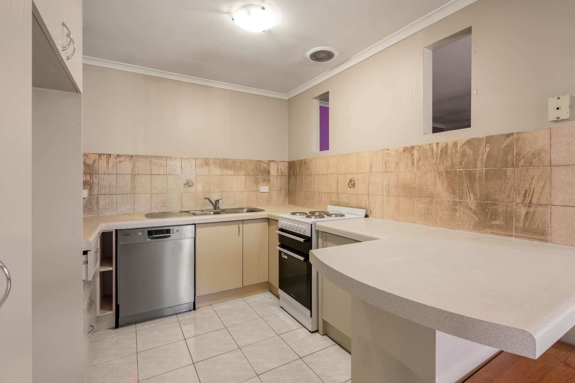 Interior entryway with open wooden door, tiled floor, carpeted living area, and a view of a tree outside.