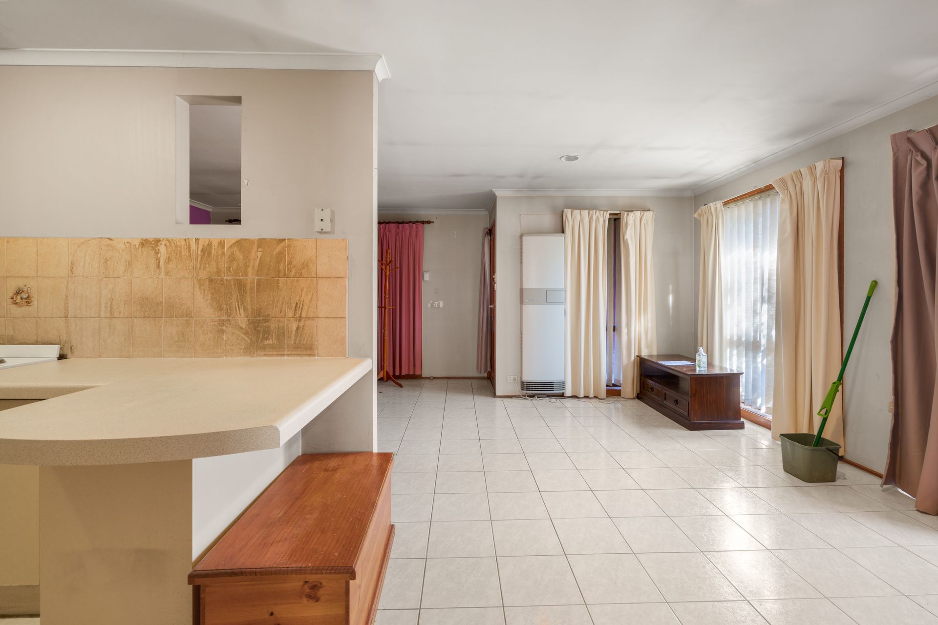 Bathroom with wooden vanity, sink, mirror, and open door to the left.