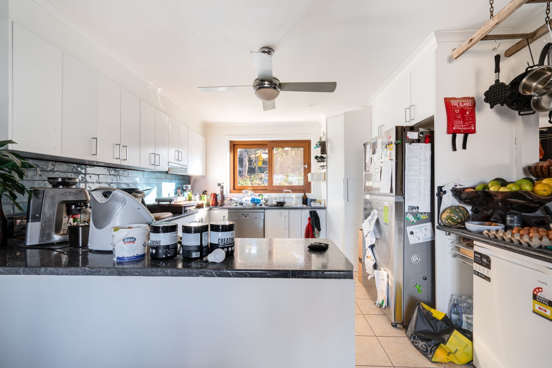 Interior entryway with open wooden door, tiled floor, carpeted living area, and a view of a tree outside.
