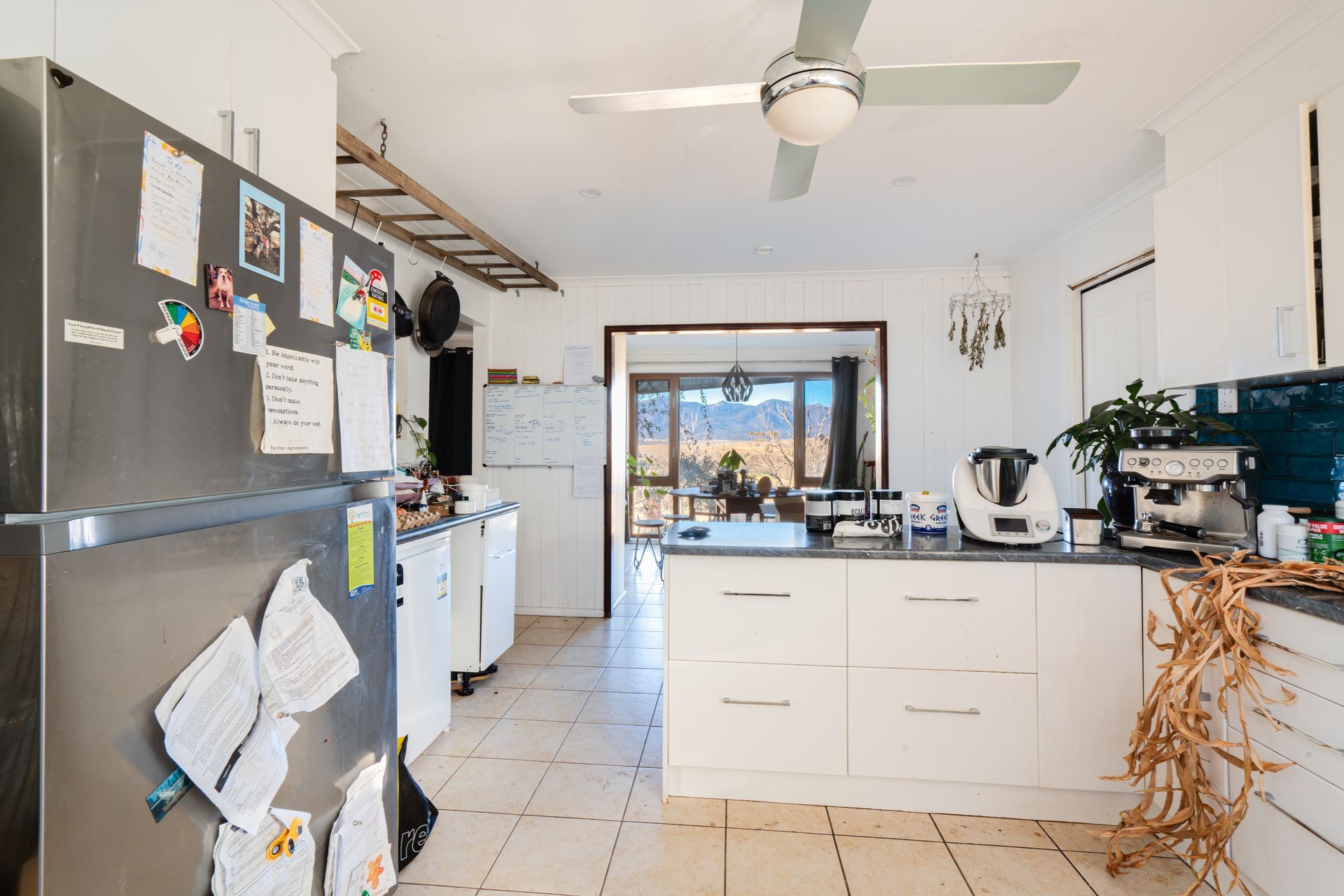 Bedroom with bed, stacked cushions, window, and small cabinet.