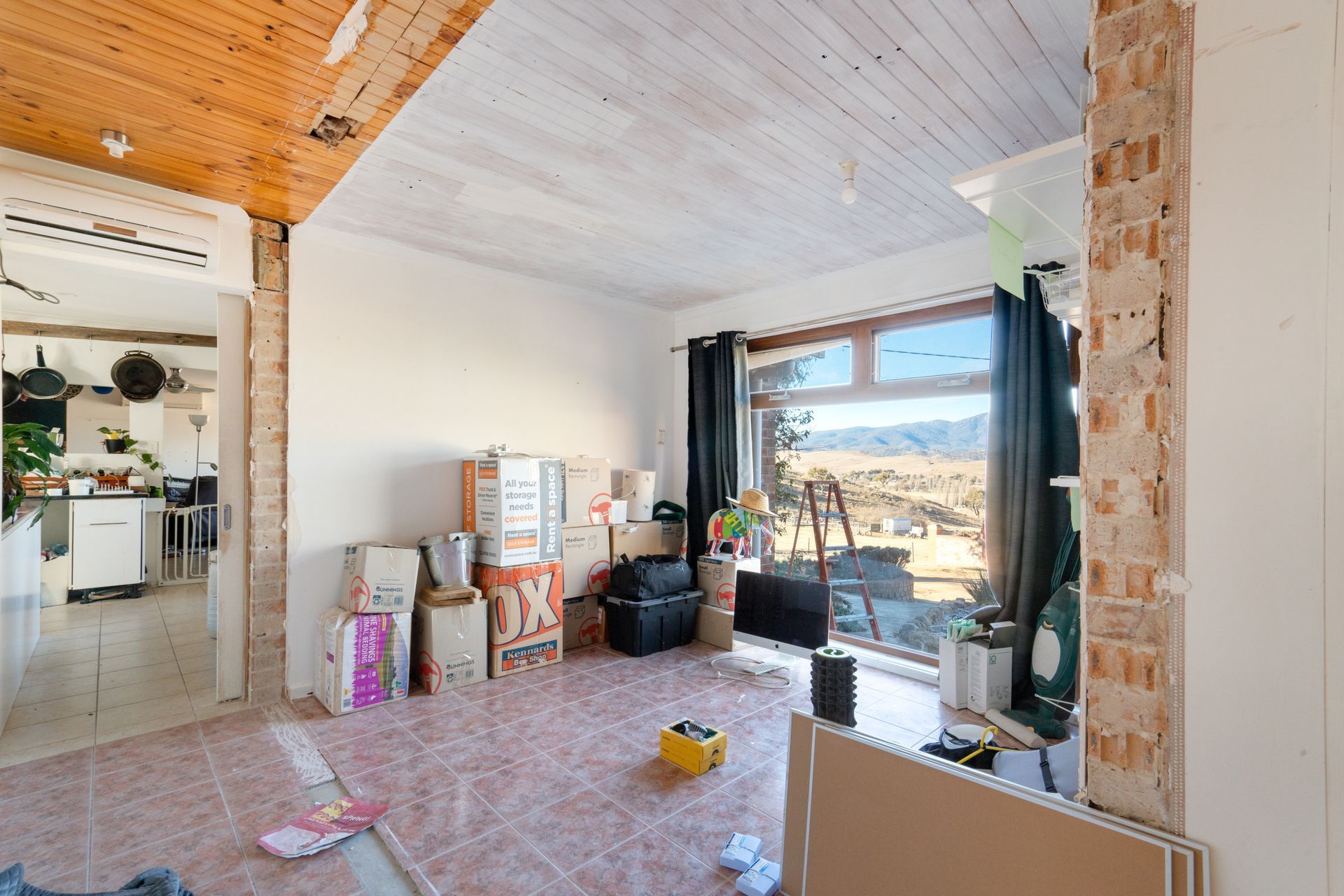 Interior entryway with open wooden door, tiled floor, carpeted living area, and a view of a tree outside.