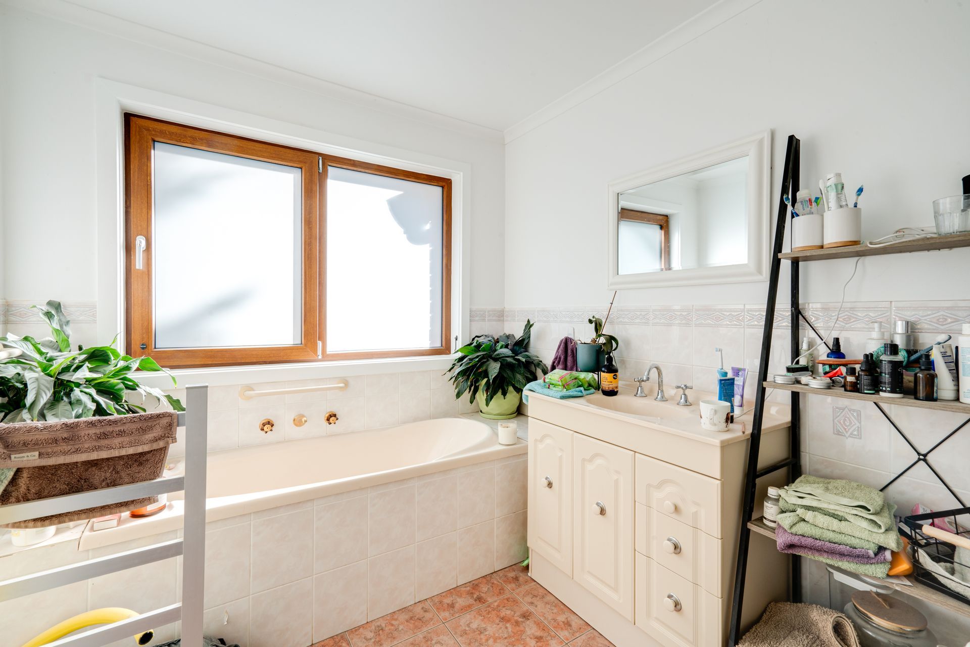 Bathroom with tub, shower, and vanity. Pale blue tiled walls, window, and neutral tones.