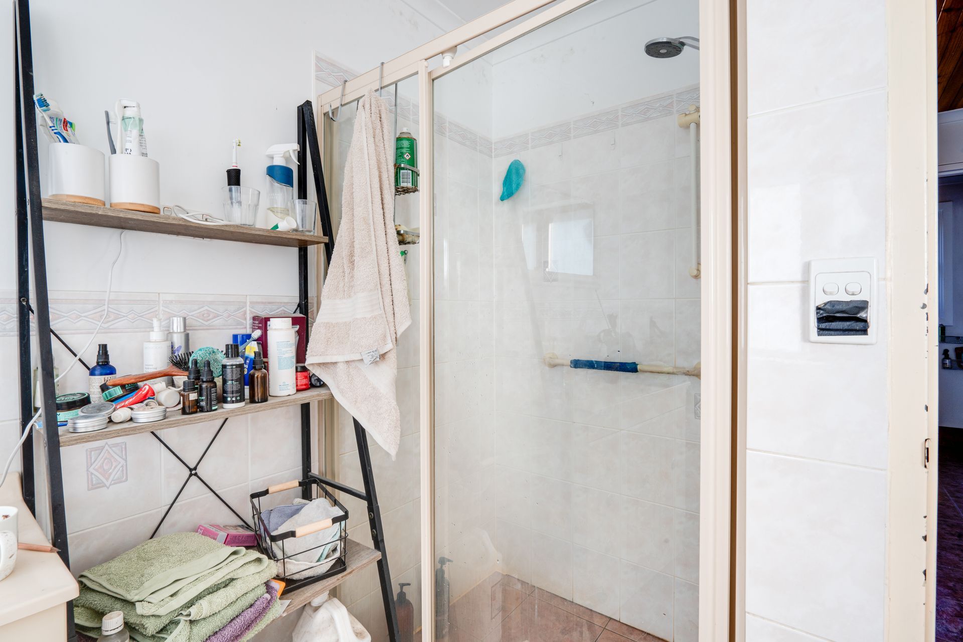 Living room with white couches, TV, and miscellaneous items scattered about.