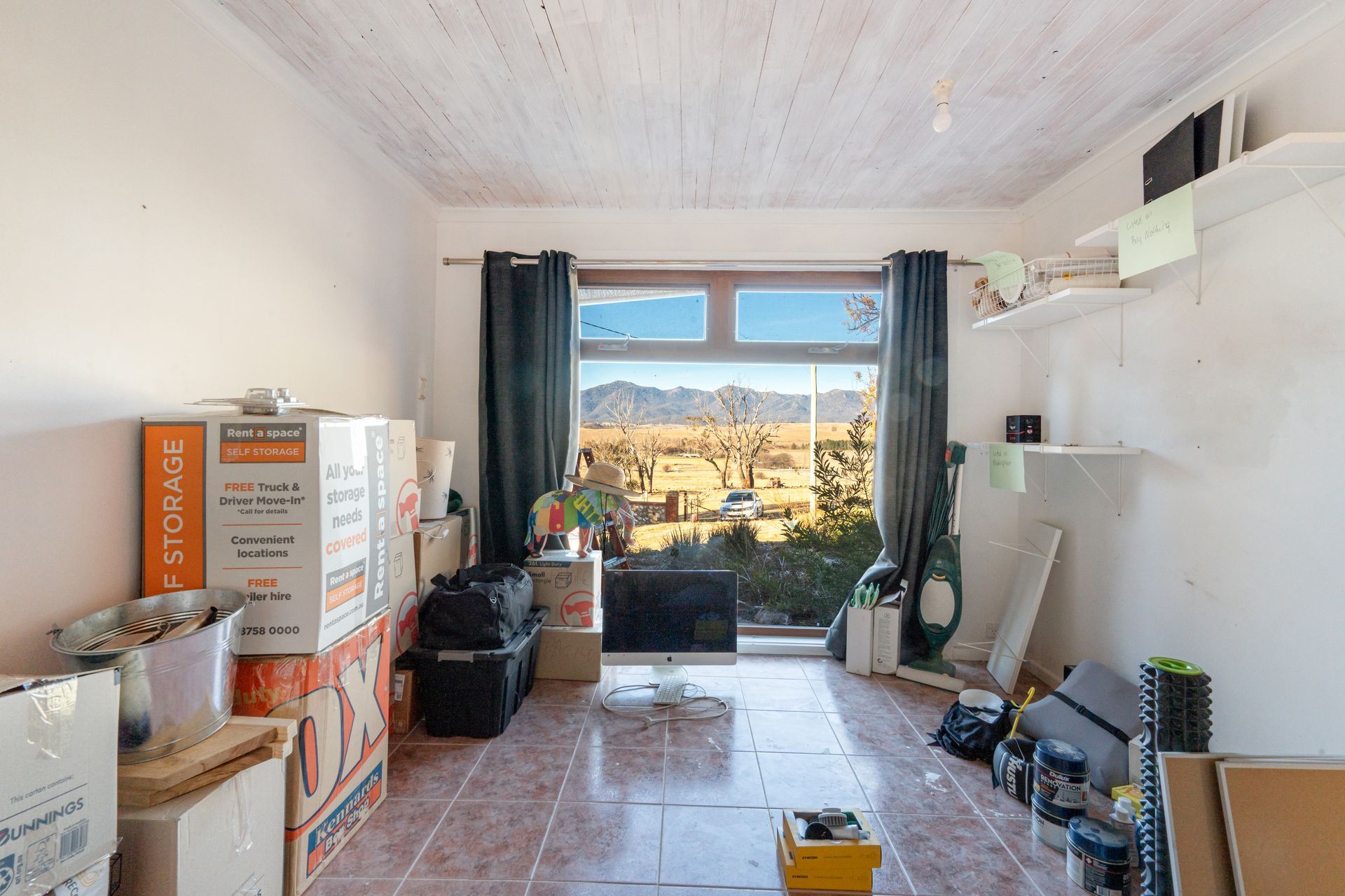 Interior entryway with open wooden door, tiled floor, carpeted living area, and a view of a tree outside.