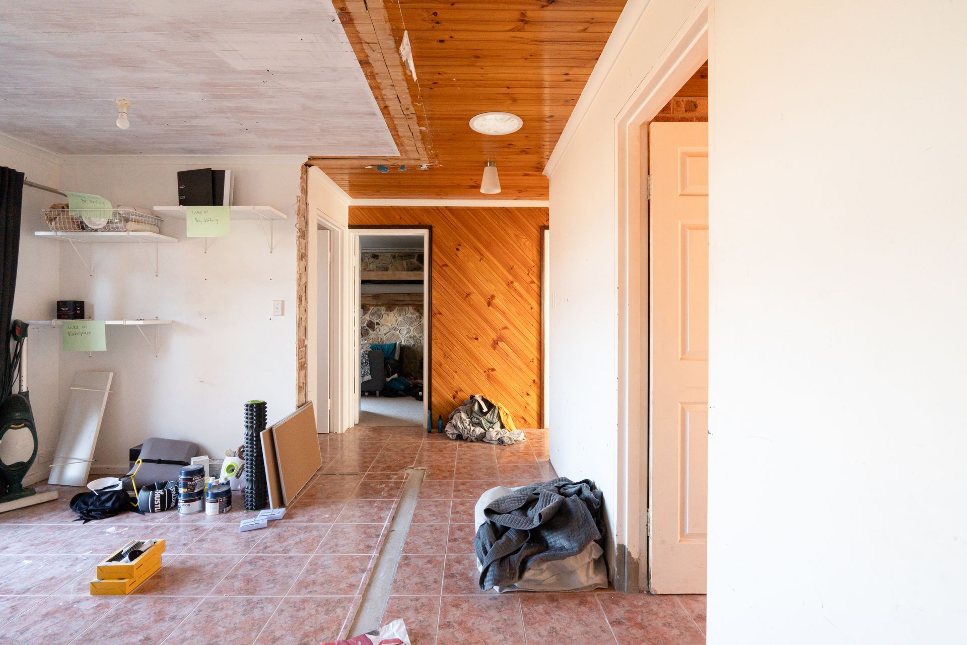 Bedroom with bed, stacked cushions, window, and small cabinet.