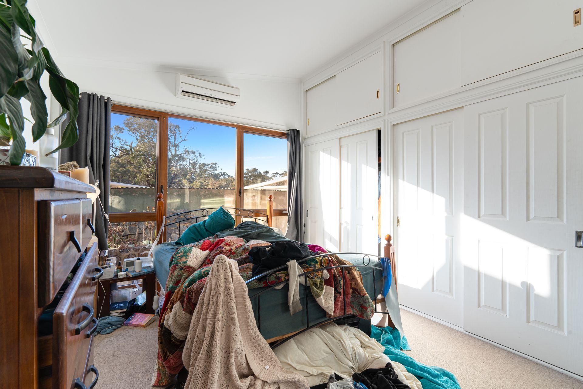 Beige house with gravel driveway, carport, and wooden fence under a cloudy sky.