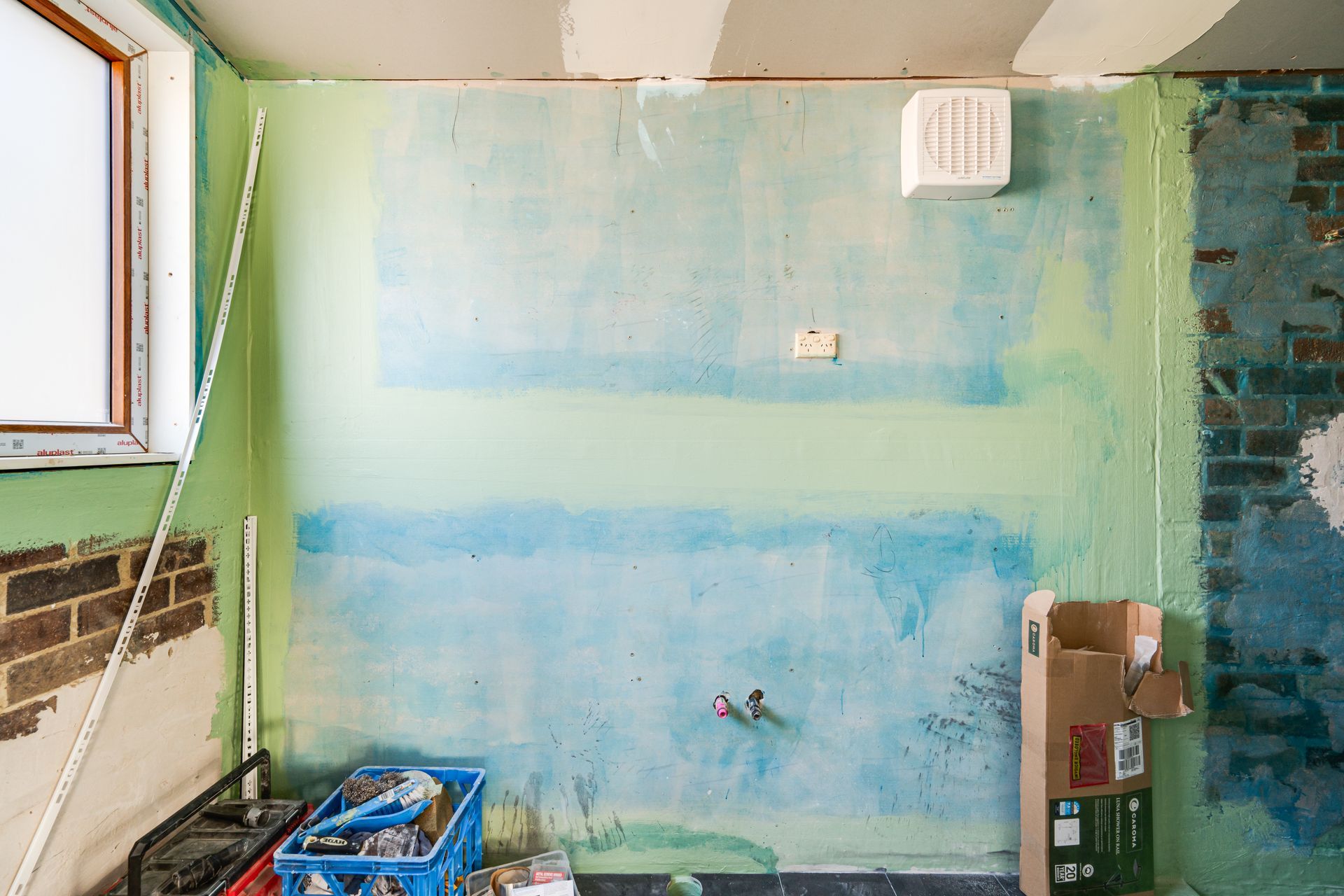 Bedroom with bed, stacked cushions, window, and small cabinet.