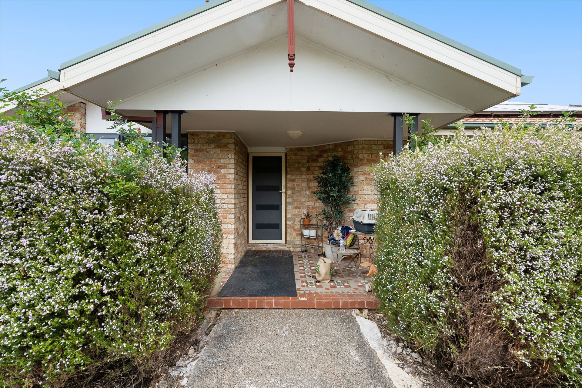 Laundry room with washing machine, sink, shelves holding cleaning supplies, and laundry baskets.