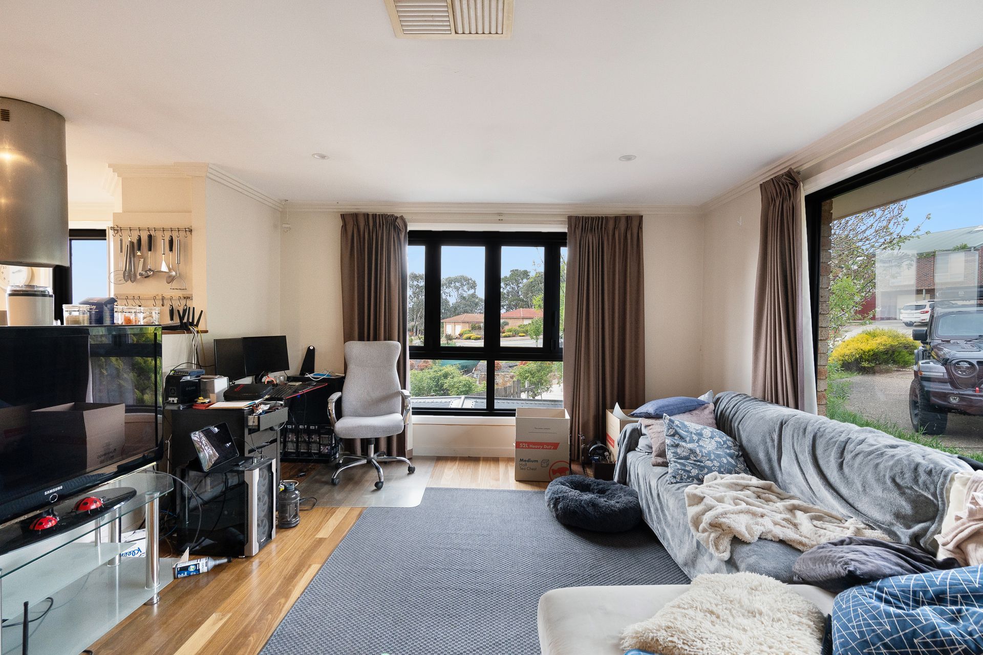 Bedroom with bed, stacked cushions, window, and small cabinet.