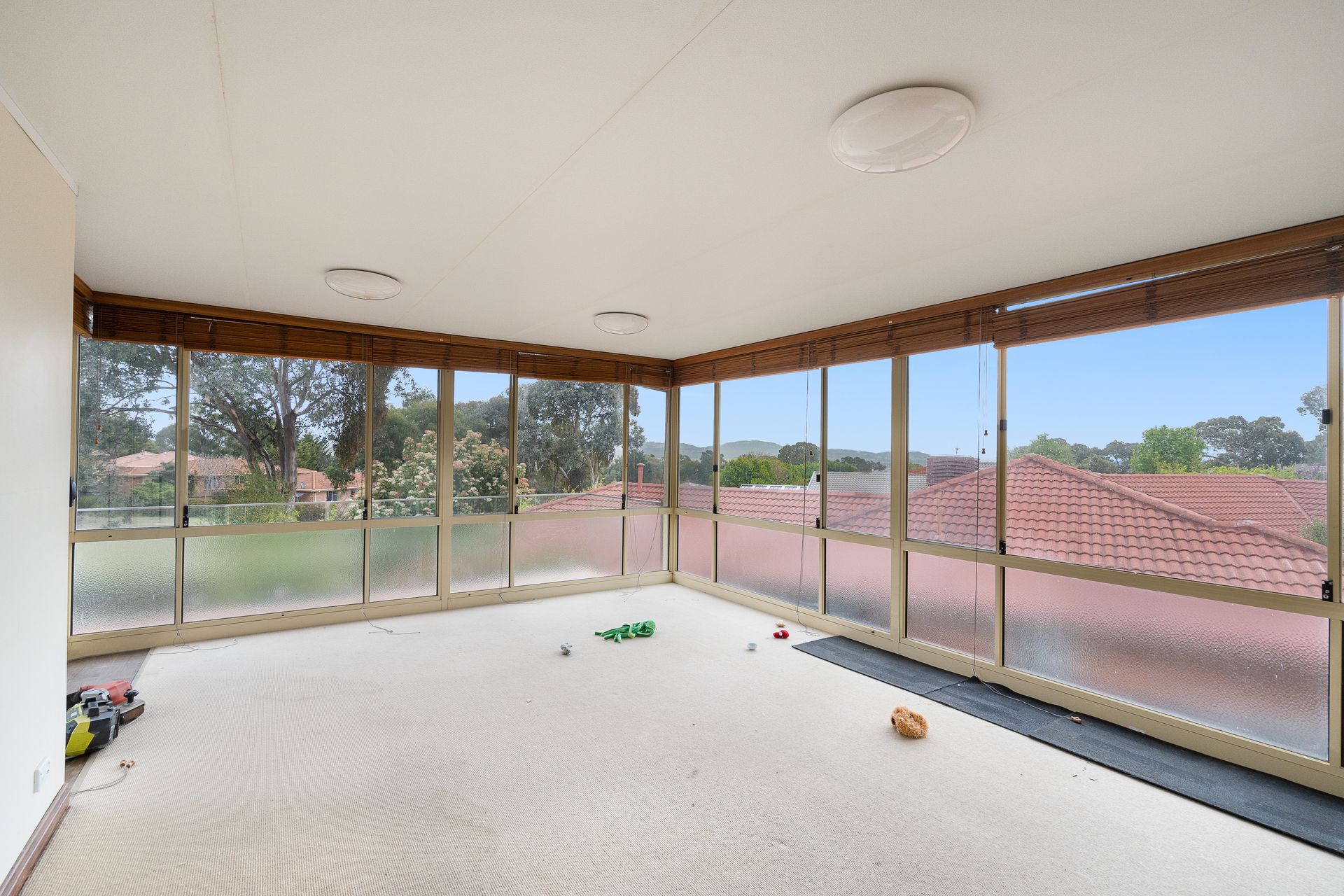 Interior entryway with open wooden door, tiled floor, carpeted living area, and a view of a tree outside.