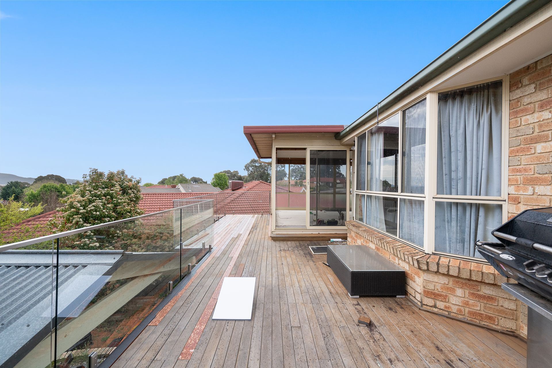 Bedroom with bed, stacked cushions, window, and small cabinet.