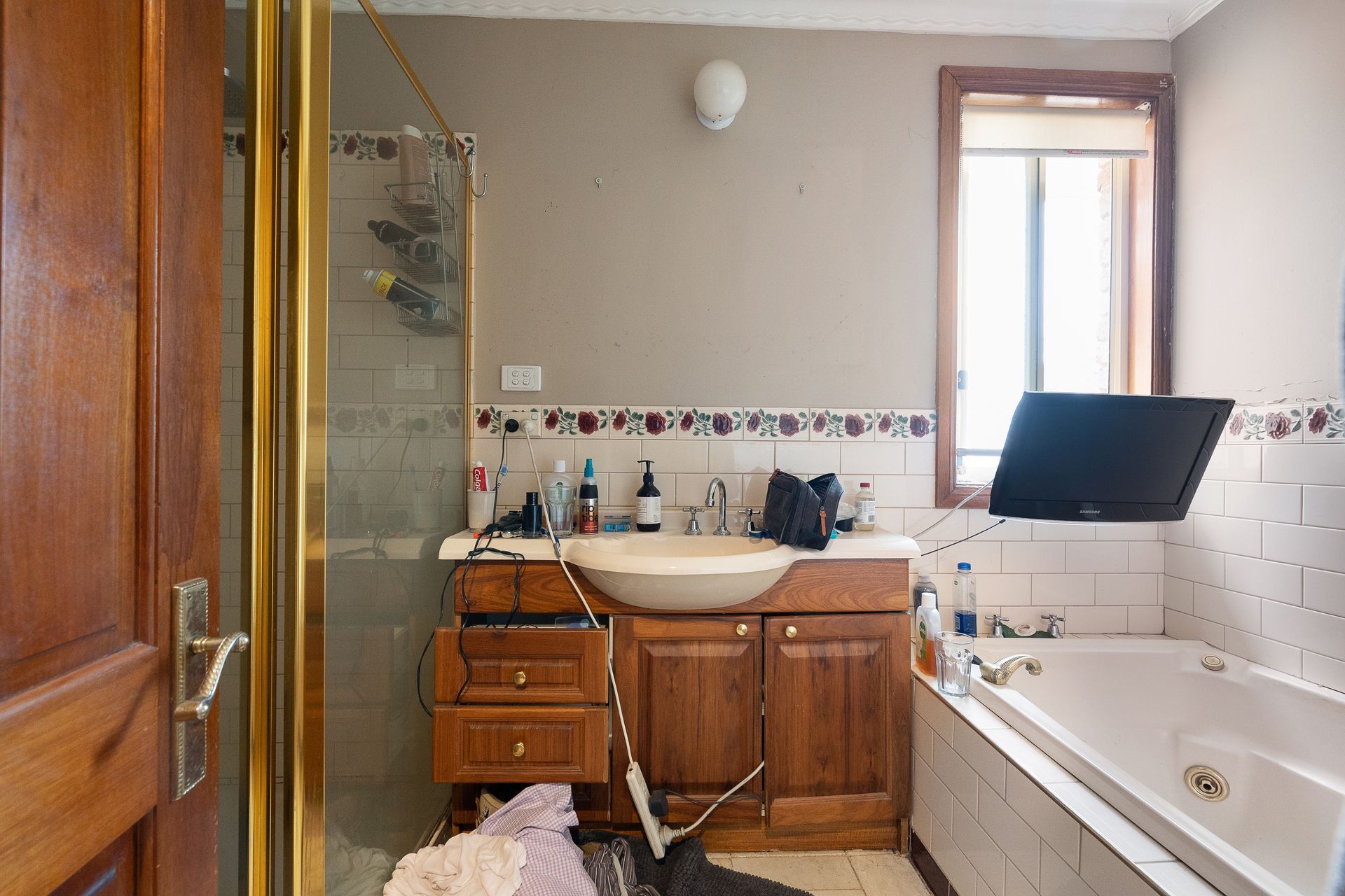 Dilapidated utility room with a sink, counter, and peeling wallpaper.