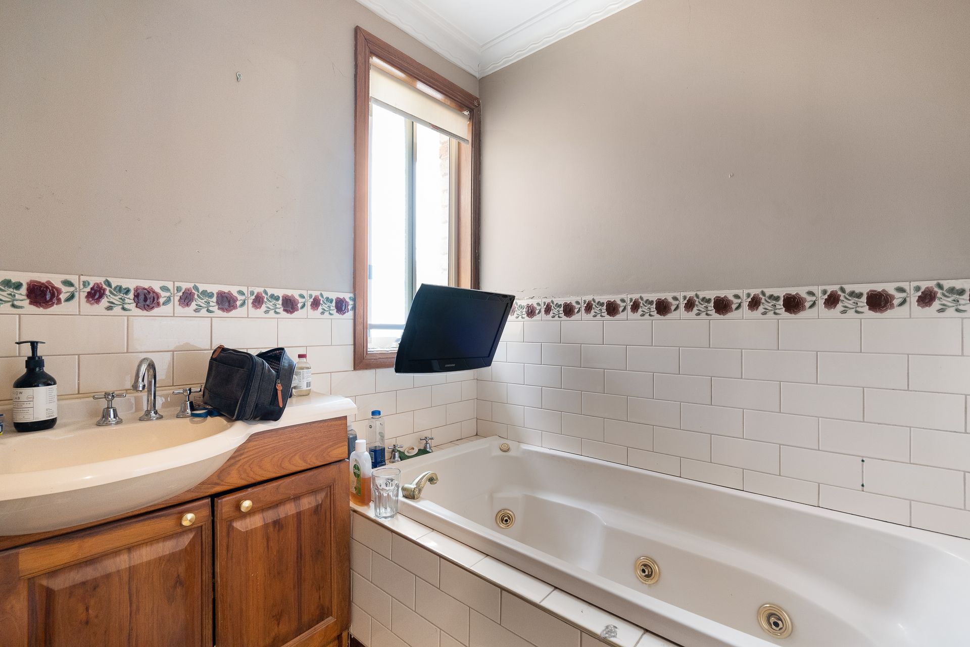 Bathroom with wooden vanity, sink, mirror, and open door to the left.