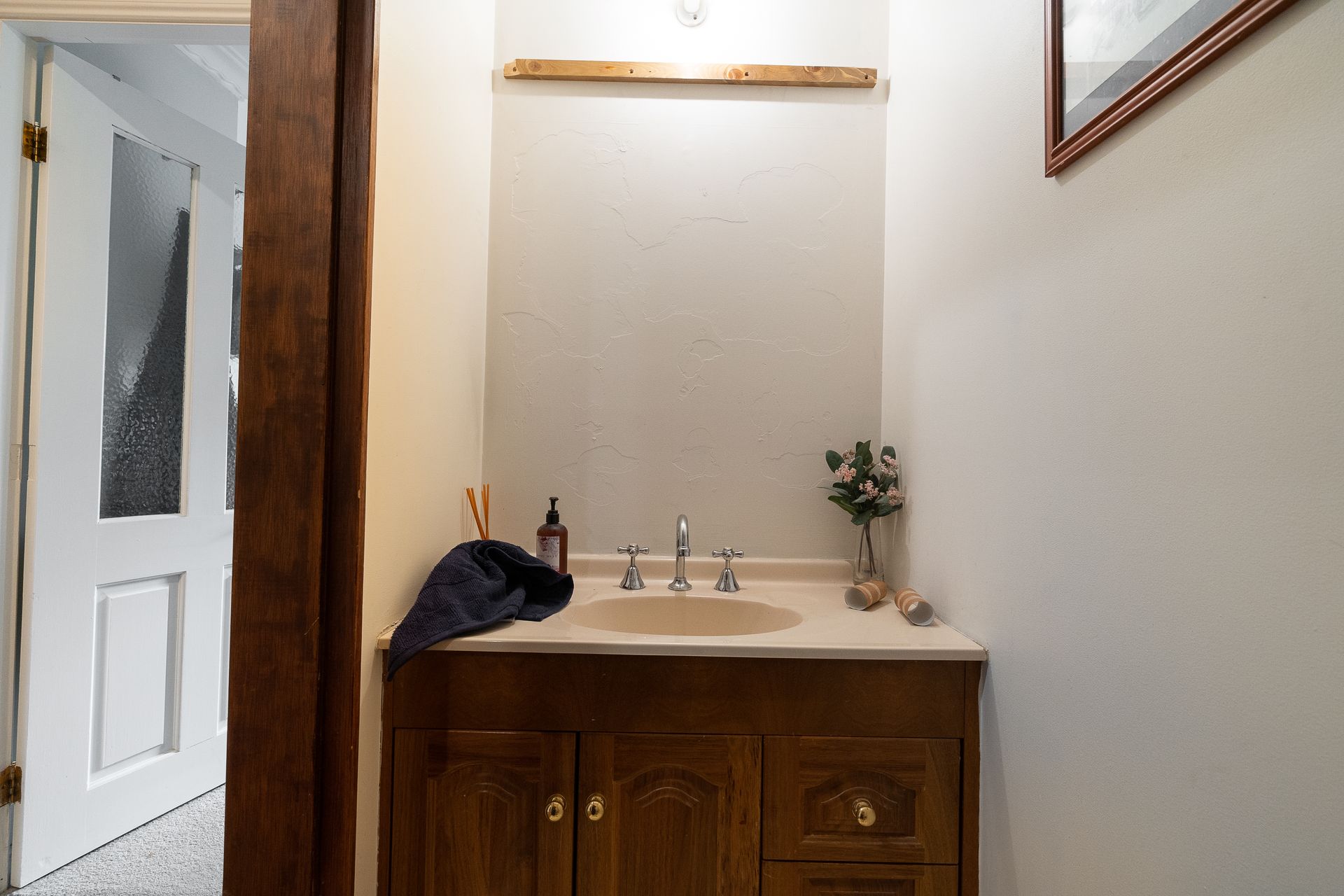 Laundry room with washing machine, sink, shelves holding cleaning supplies, and laundry baskets.