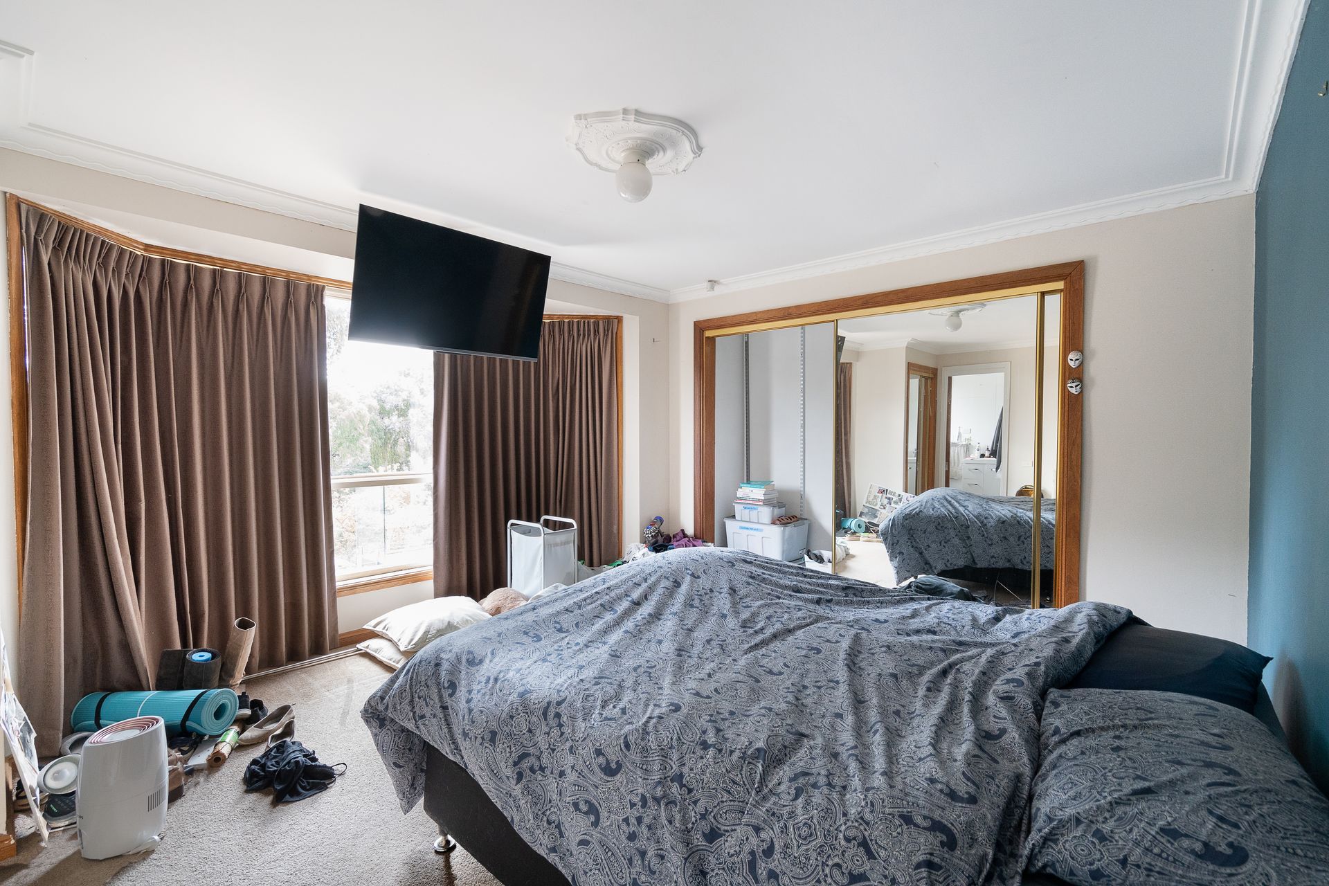 Bathroom with wooden vanity, sink, mirror, and open door to the left.