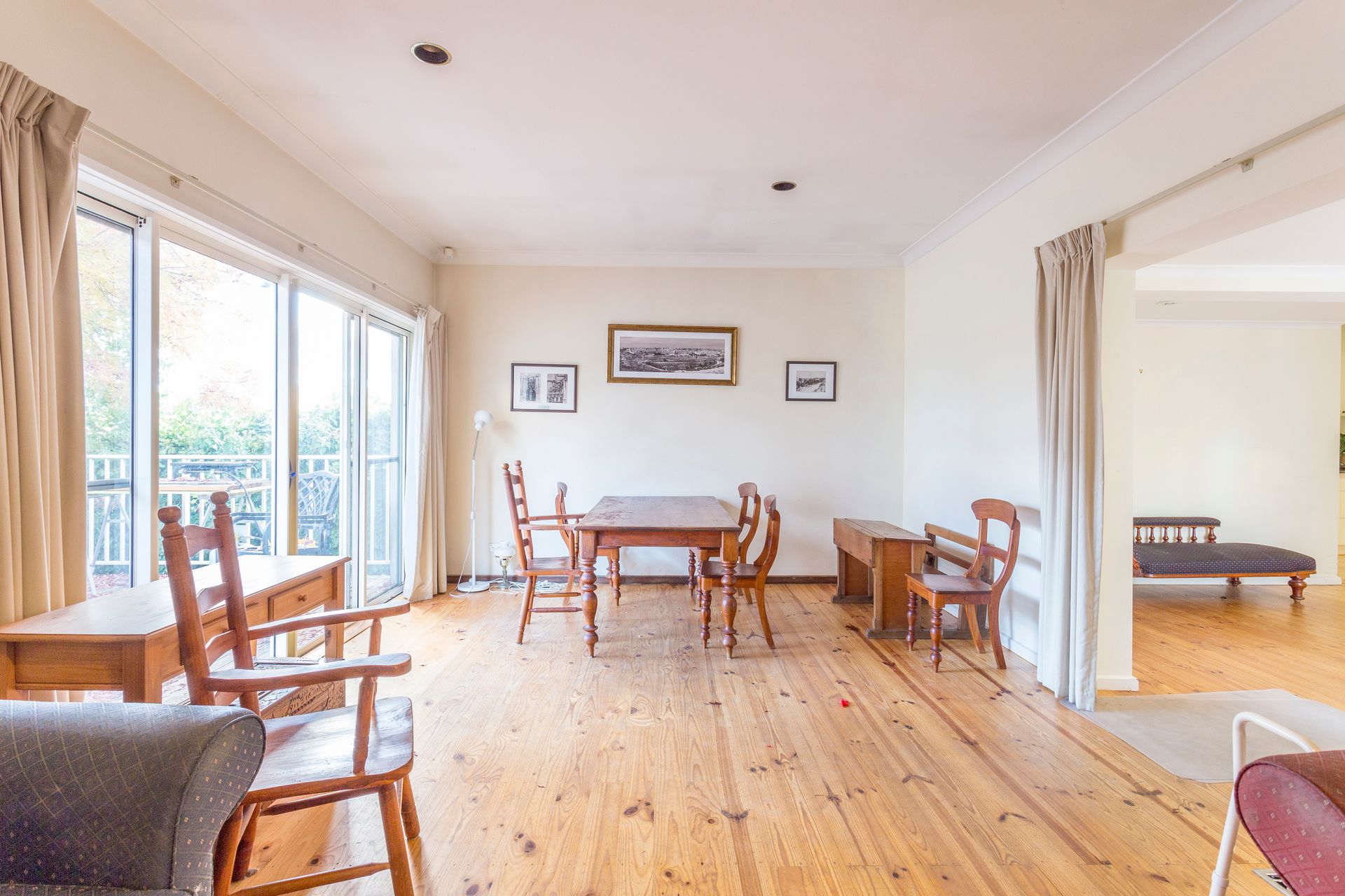 Dining room with wooden furniture, sliding door to balcony, and entrance to another room.