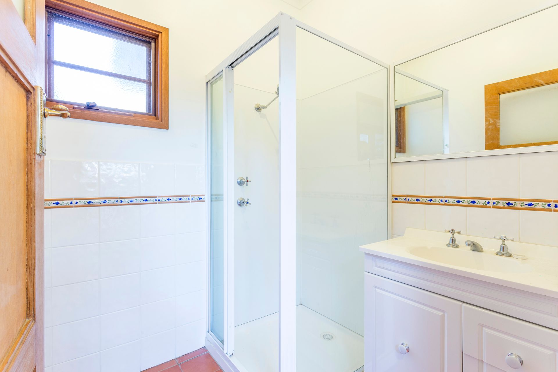 Living room with open doors to a balcony, light grey couches, and colorful artwork.