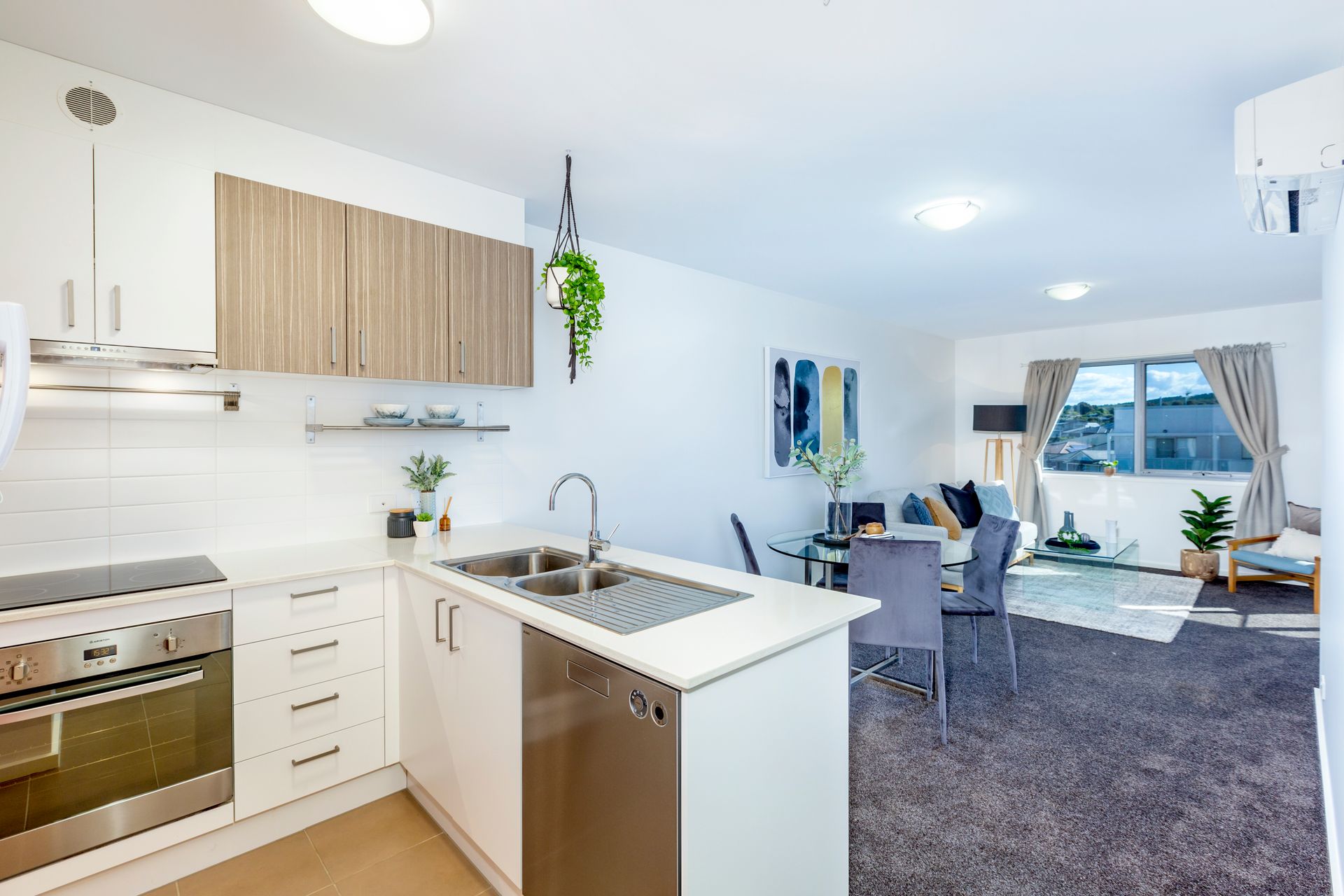 Modern kitchen with white cabinets, stainless steel appliances, and adjacent living area.