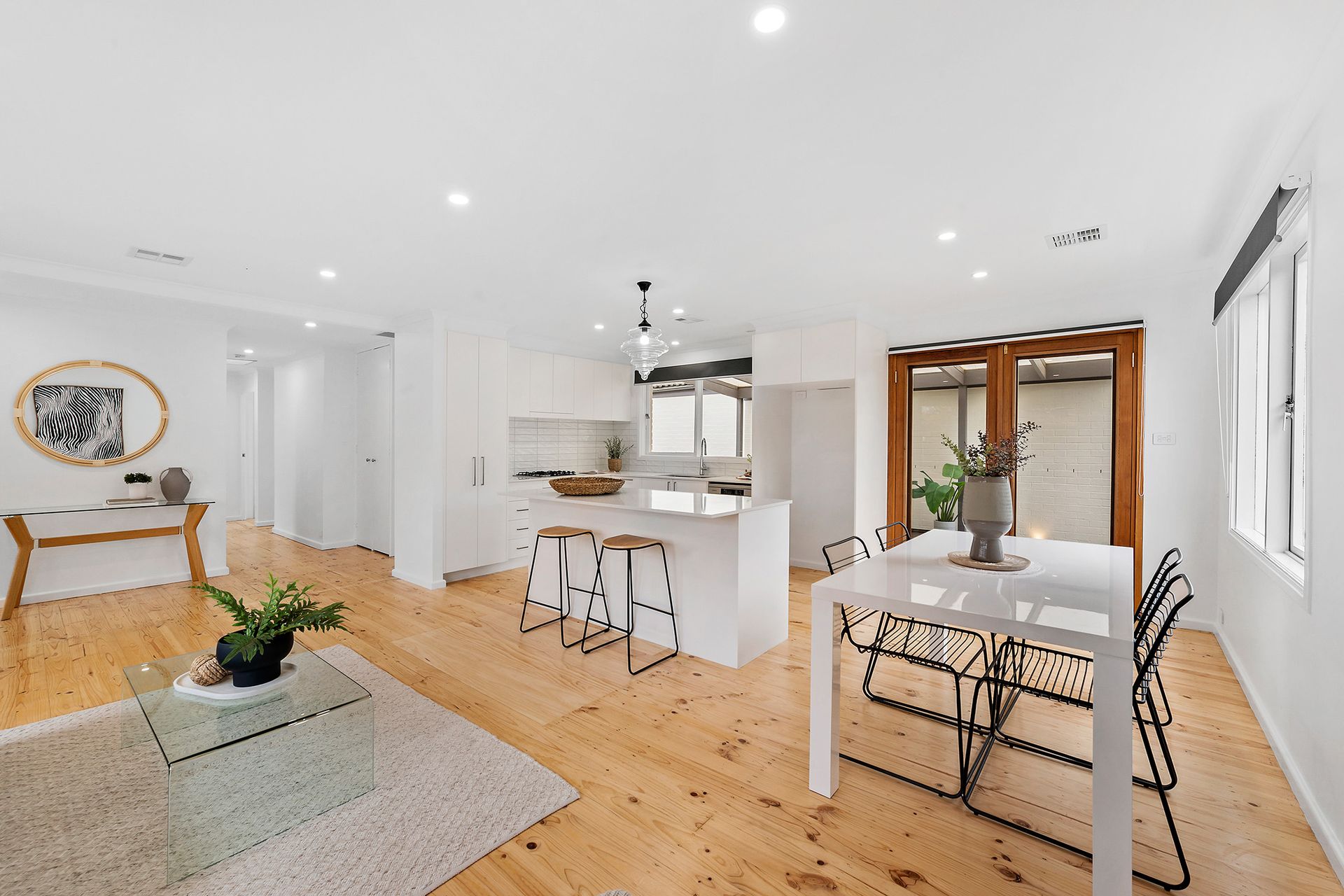 Living room with light gray walls, wooden floors, and a view of the outside through a large window.