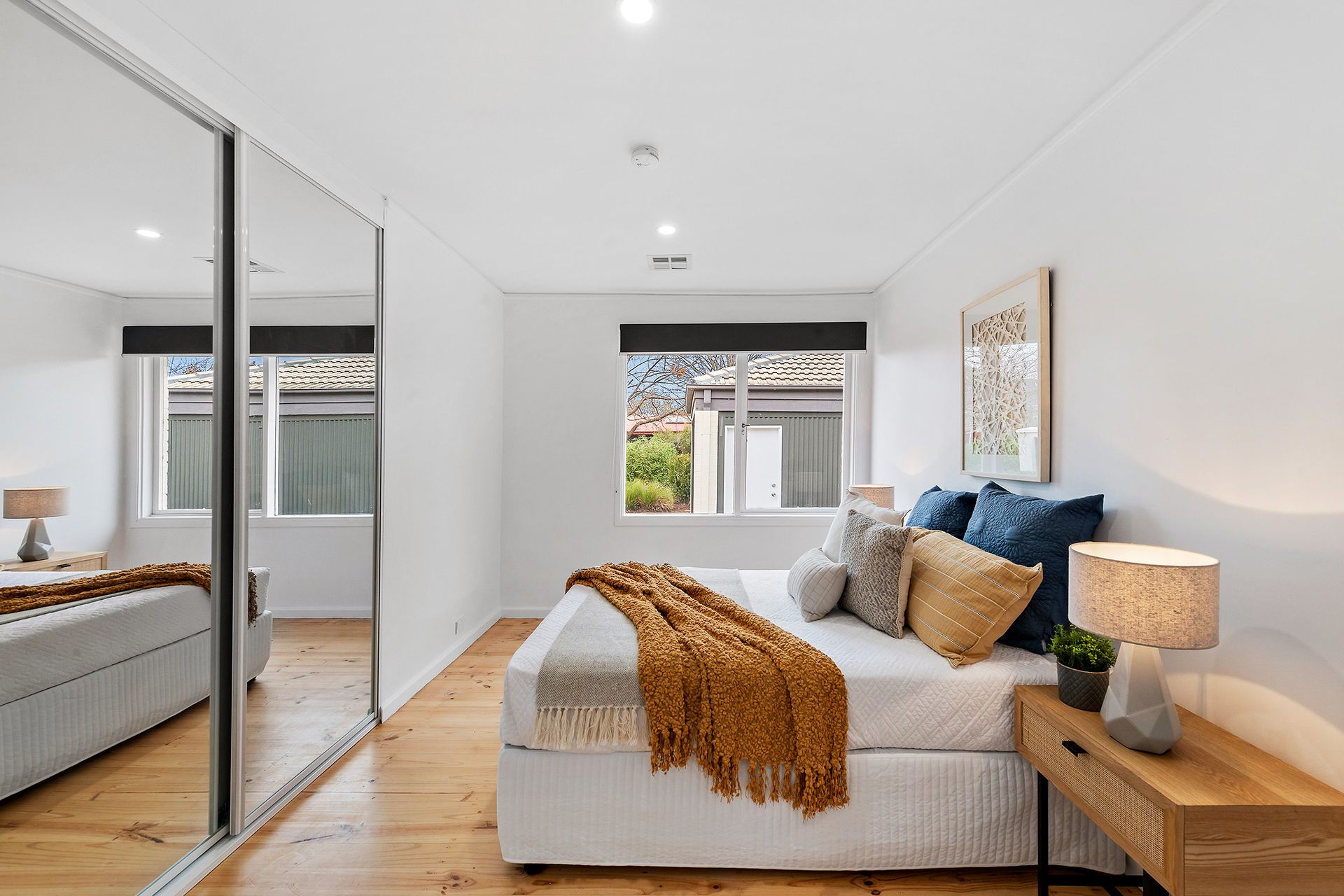 Covered patio with seating, raised garden beds, and brick wall. Sunny day, blue sky.