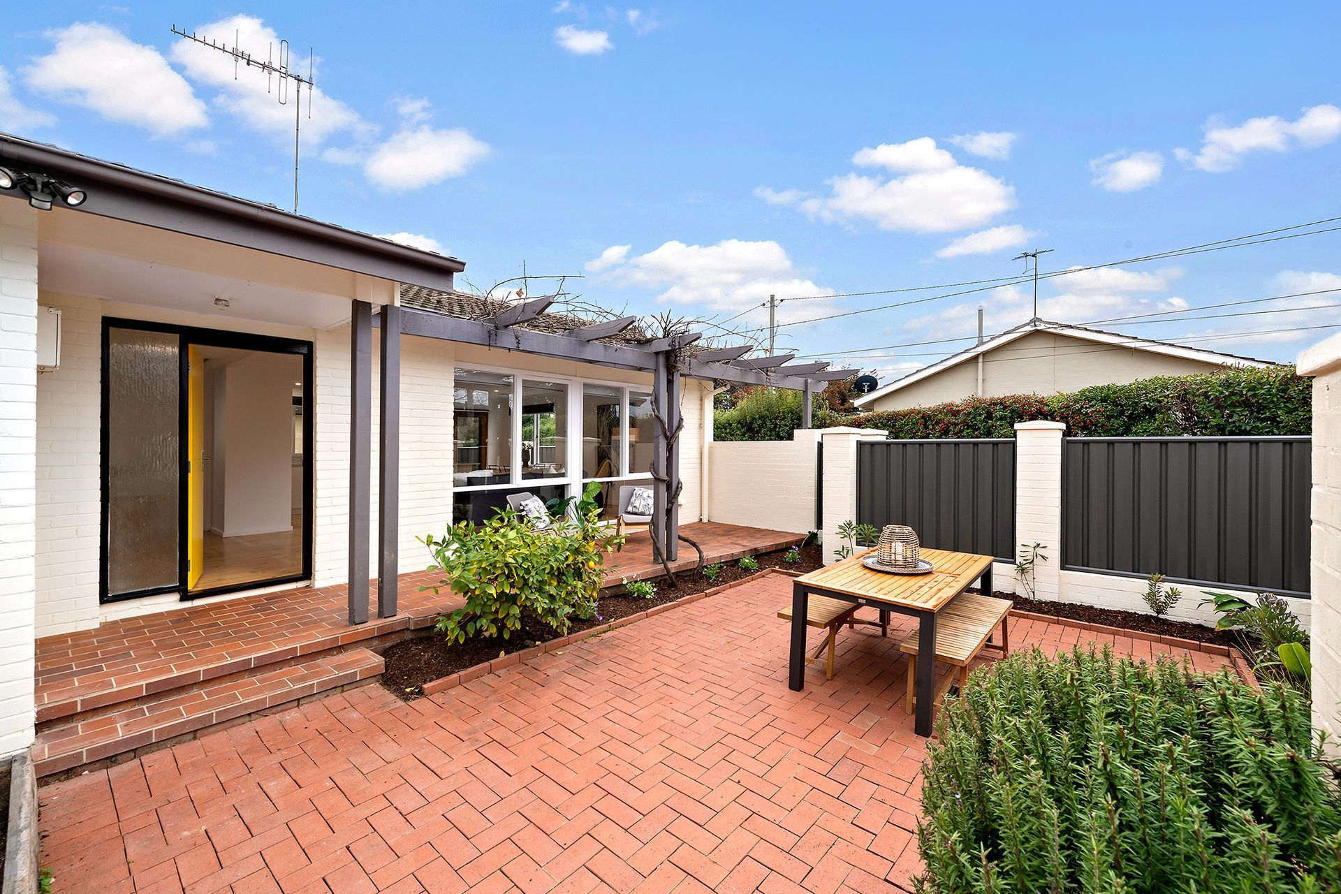 Bright kitchen with white cabinetry, island with bar stools, and wooden flooring.