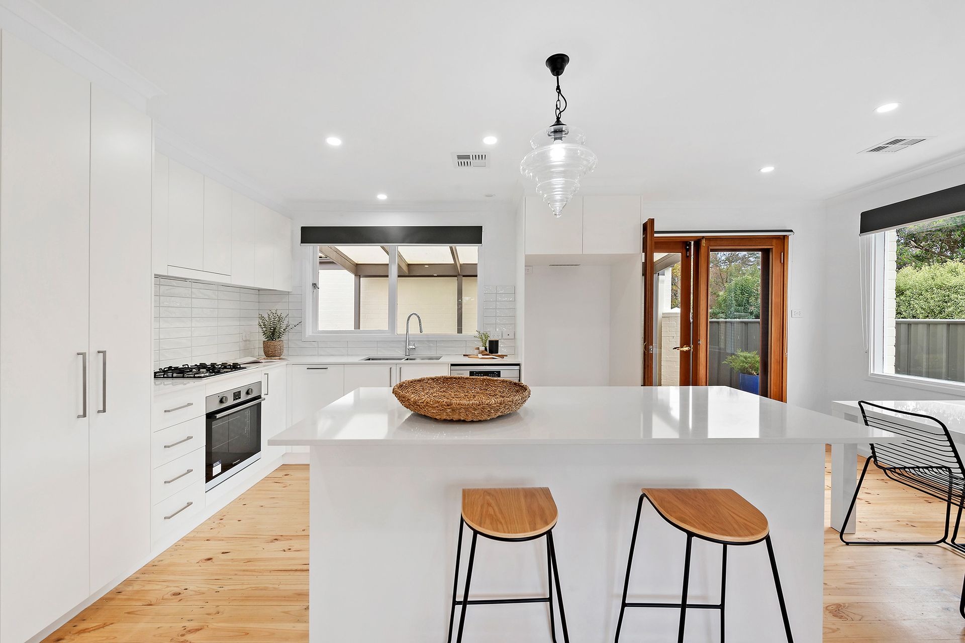 White bathroom with a frosted window, vanity, mirror, shower, and tub.