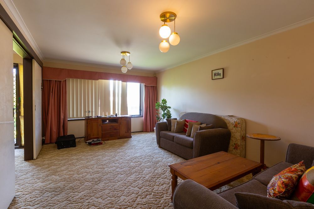 Living room with a sofa, wooden coffee table, and large window with curtains.