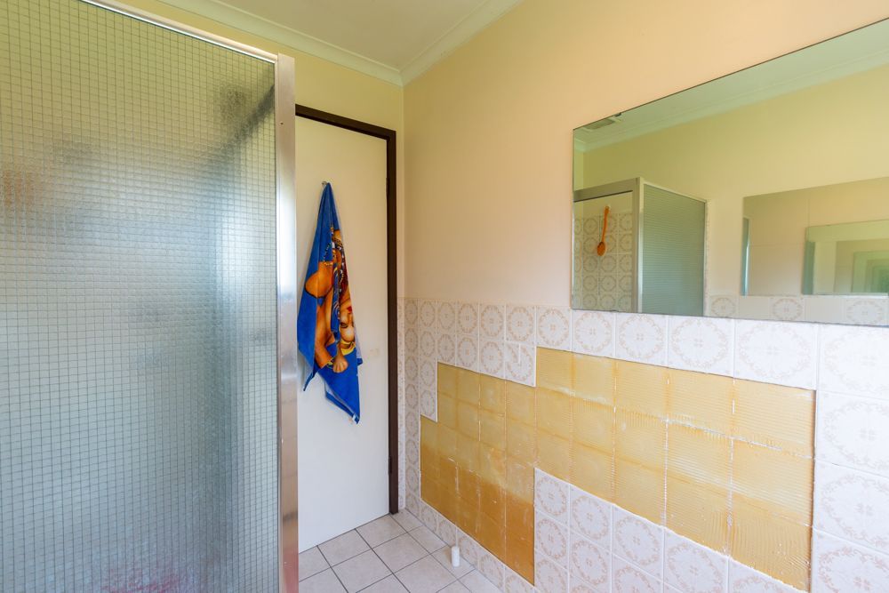 Bathroom with a frosted glass shower, a door with a towel, and missing tiles.