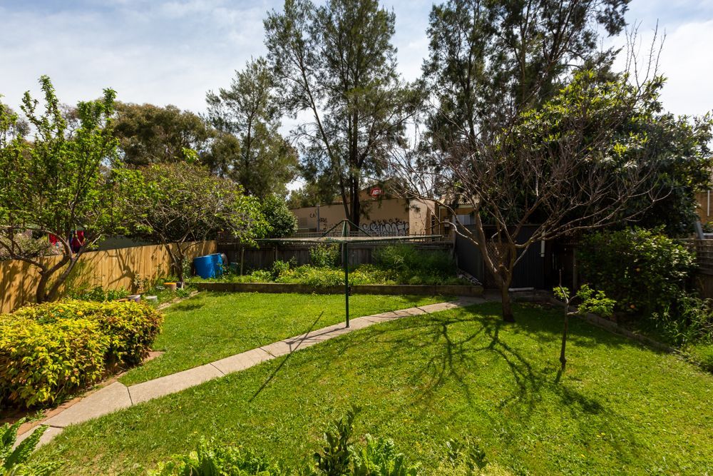 Green backyard with lawn, trees, shrubs, and clothesline.