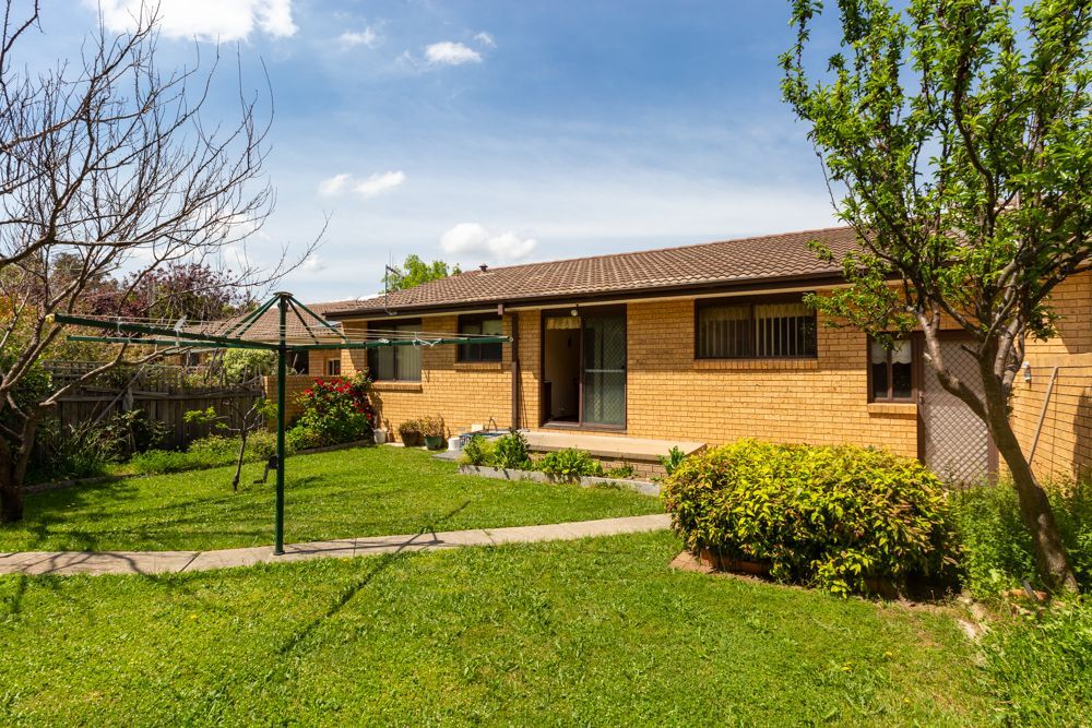 Living room with a sofa, wooden coffee table, and large window with curtains.