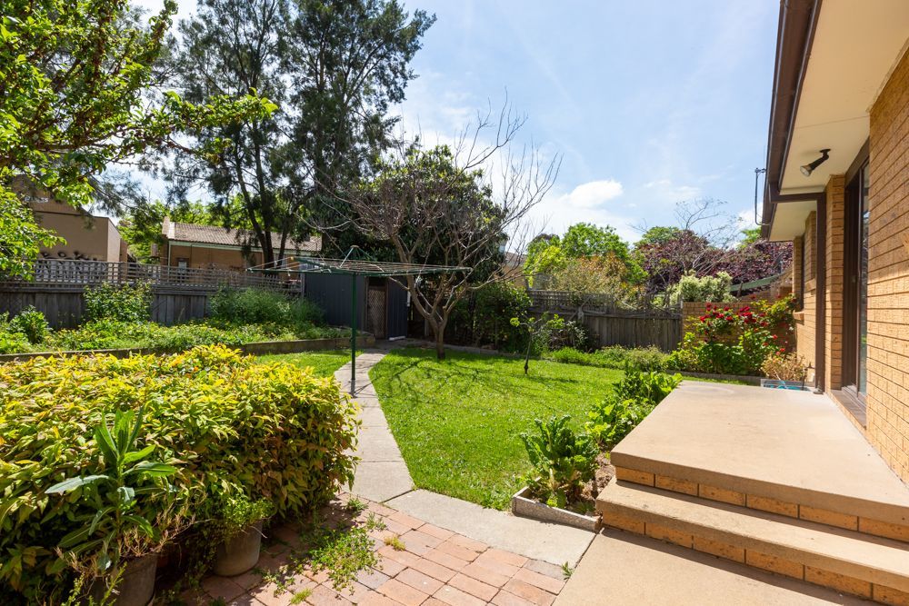 Bathroom with a white vanity, bathtub, window, and a frosted glass shower door.