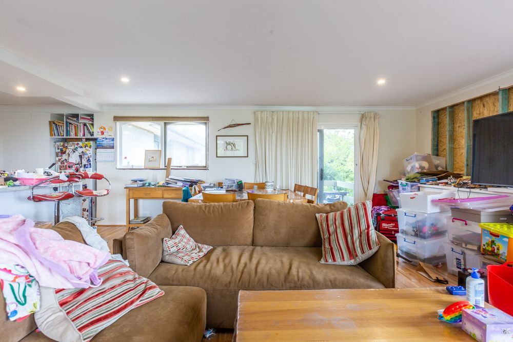 A cluttered bedroom with unmade bed, nightstand, posters, and curtains.