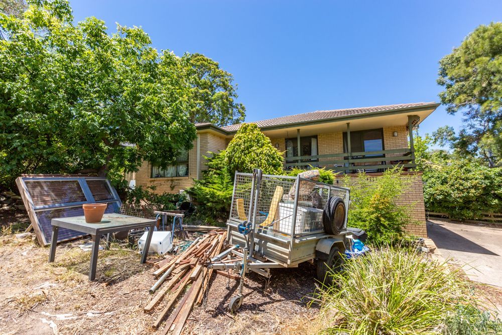 A cluttered interior with a kitchen, hallway, and various storage items against wooden floors.