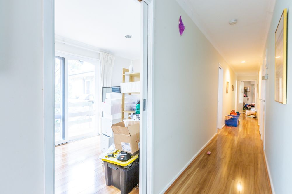 Cluttered dining room with table covered in clothes and items; two framed art pieces on the wall.