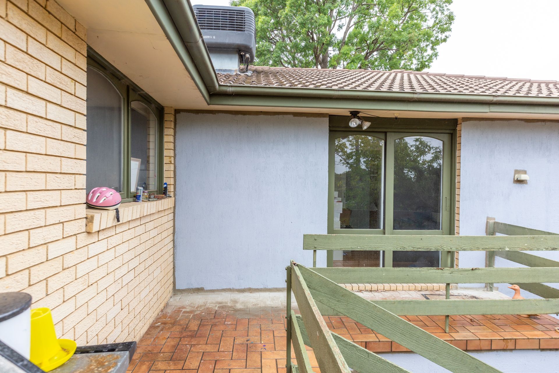 Messy bedroom with wardrobe, dresser covered in clothes, fan, and cluttered floor.