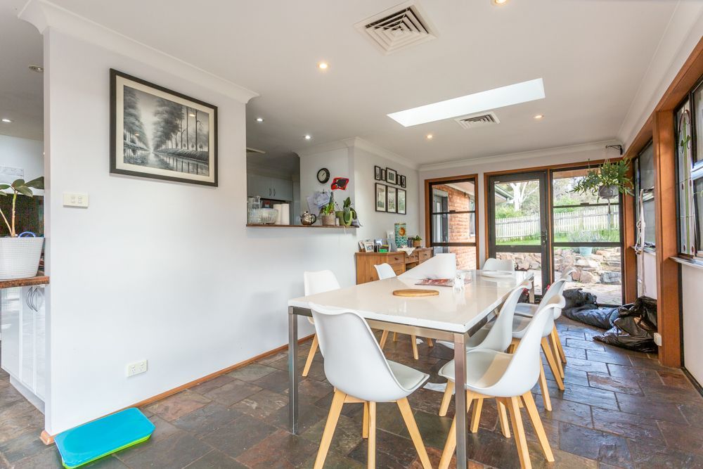 Dining room with white table and chairs, skylight, and doorway to outdoors.