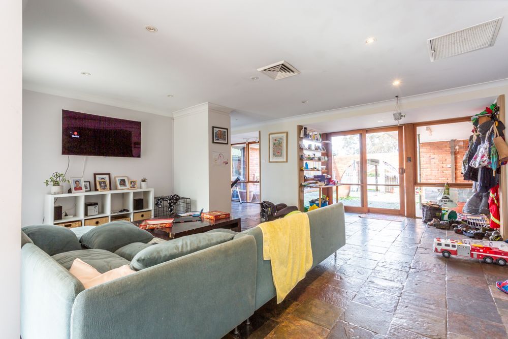 Spacious living room with blue sofa, TV, and open doorway leading to a brick patio.