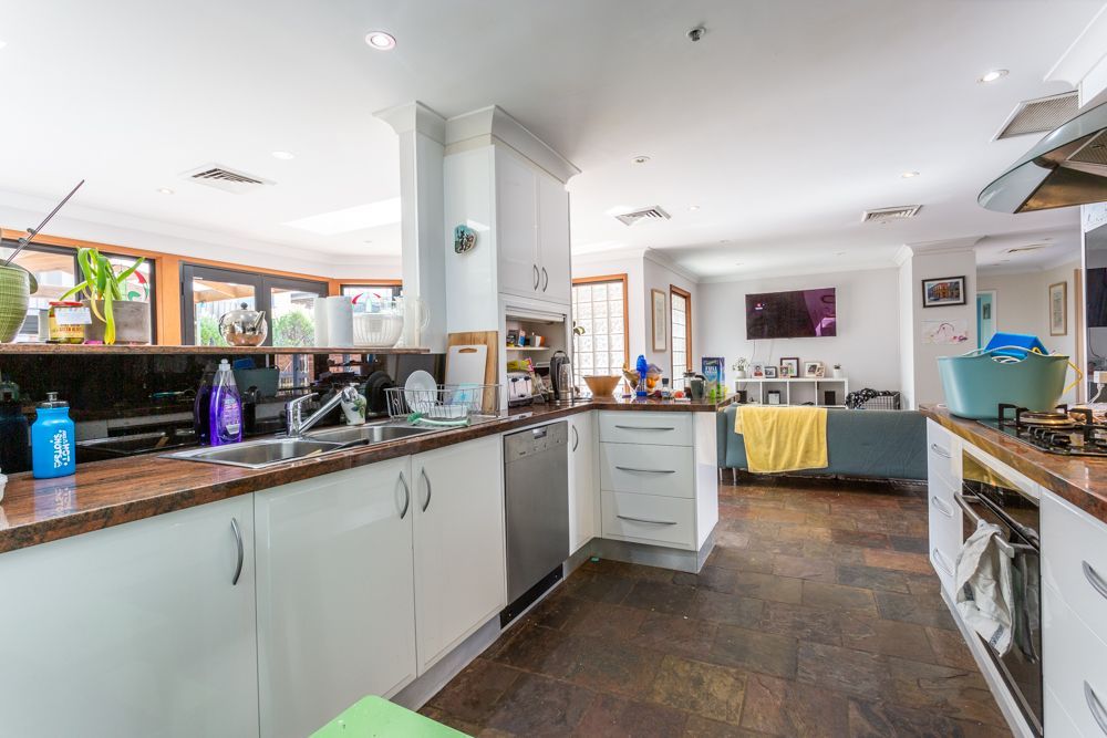 Spacious kitchen with white cabinets, dark countertops, and stainless steel appliances; leads to living area.