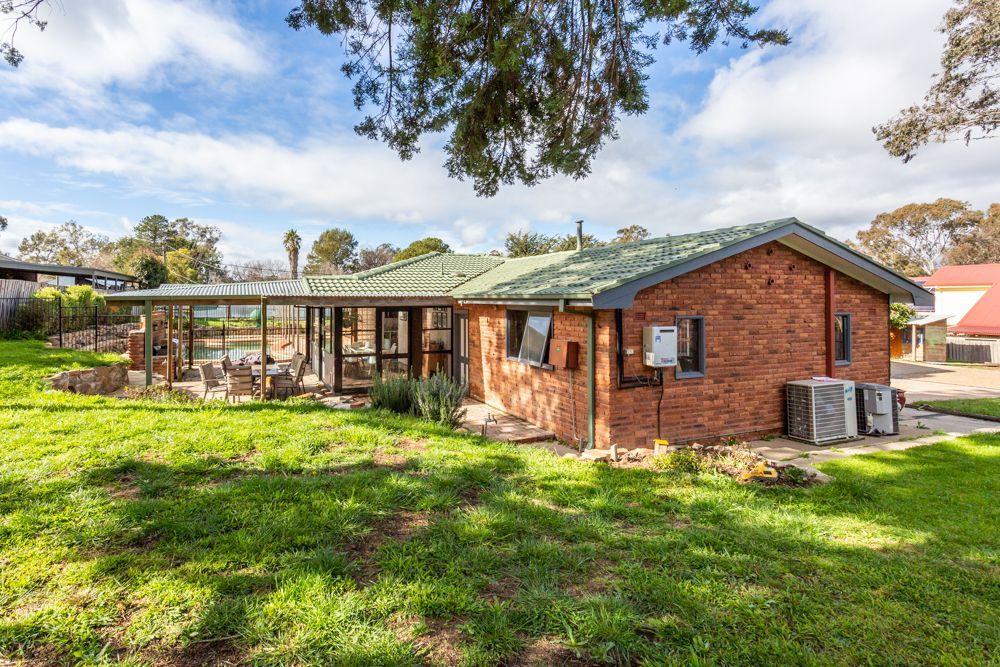 Bathroom with shower, vanity, and bathtub. Plants hang near the window and mirror. Light-colored tile and cabinets.