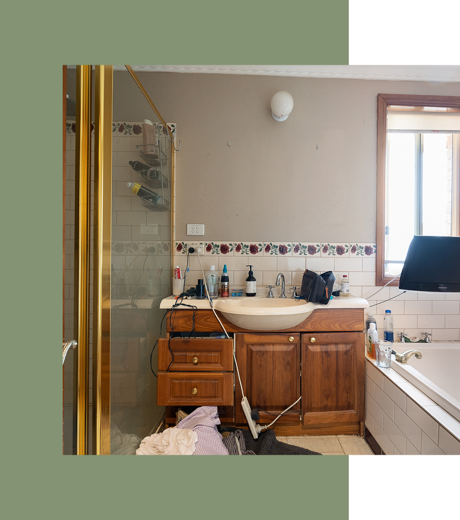 Bathroom with brown vanity, shower, and television mounted above the tub.