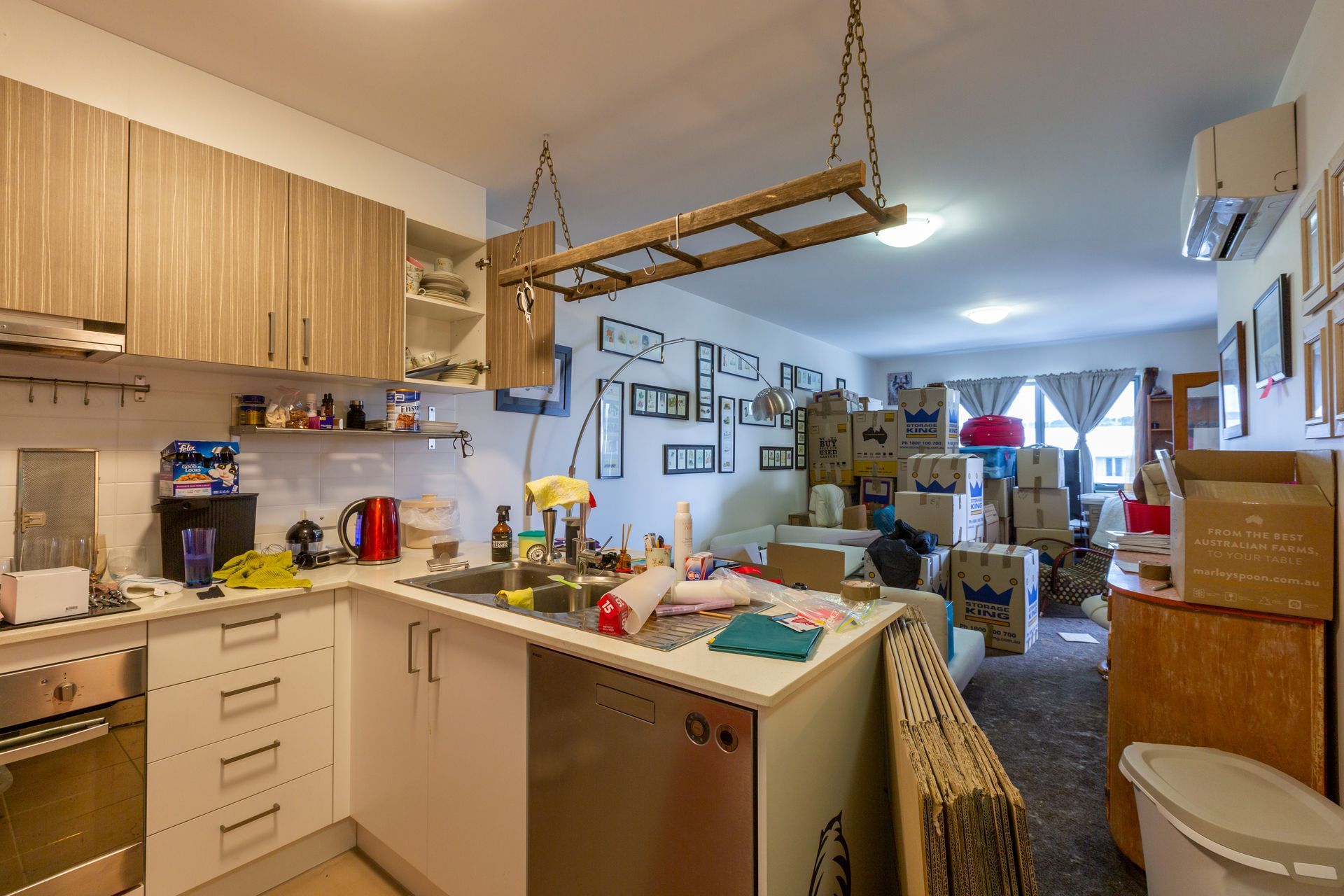 Kitchen with light wood cabinets, stainless steel appliances, and boxes, seemingly in the process of moving.