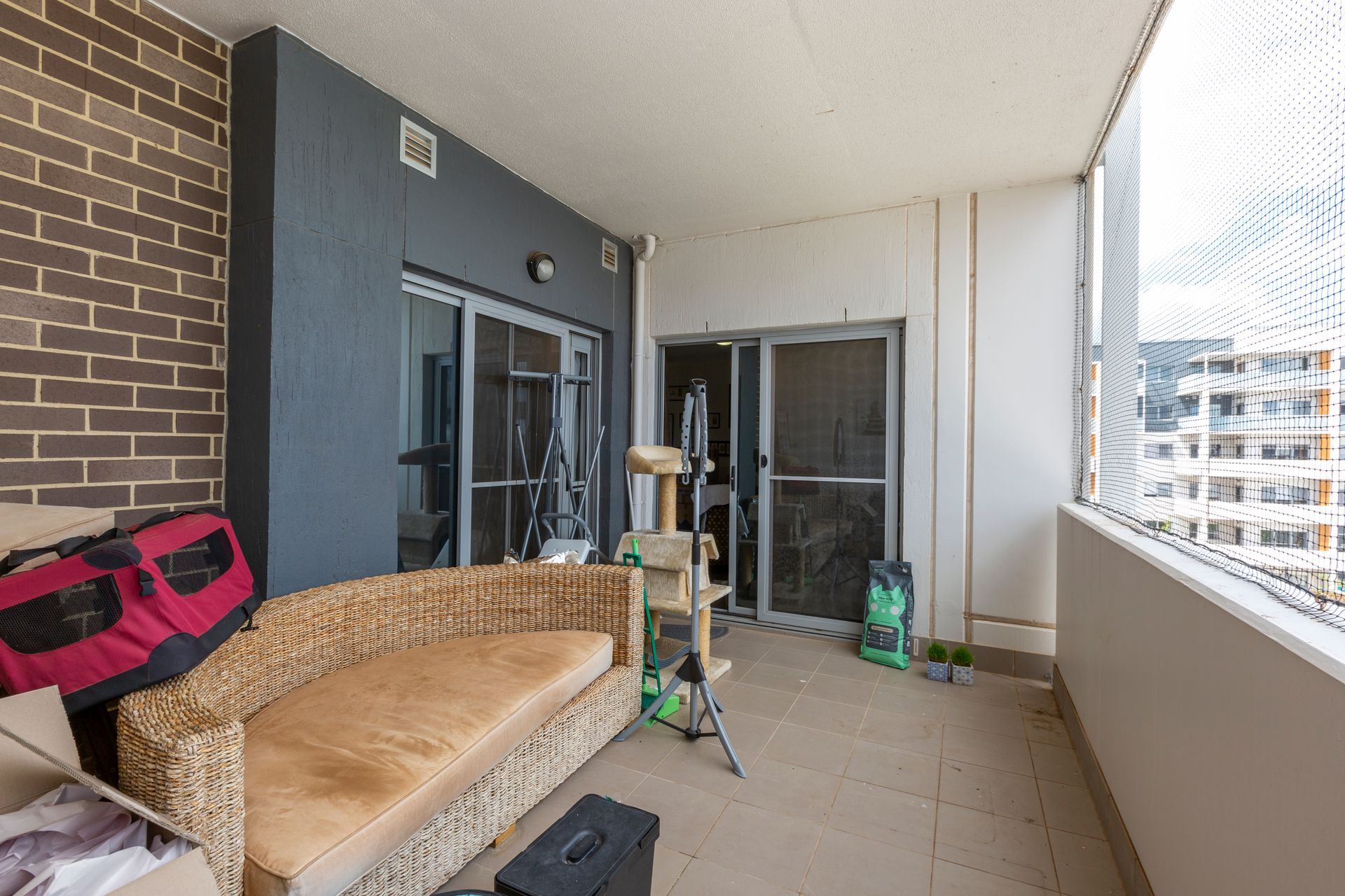 Balcony with a wicker couch, brick wall, and a view of buildings.