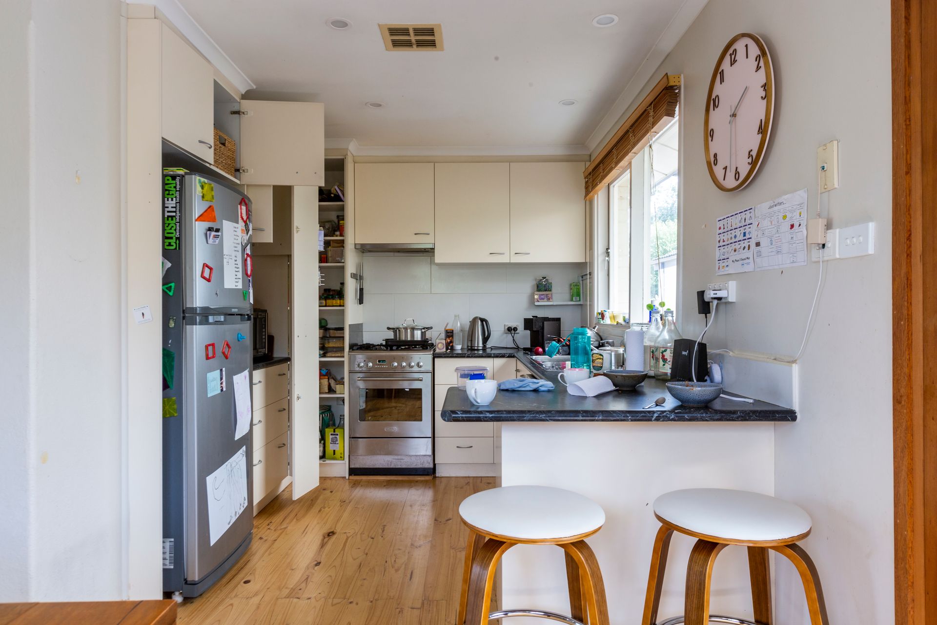 Bedroom with bed, stacked cushions, window, and small cabinet.