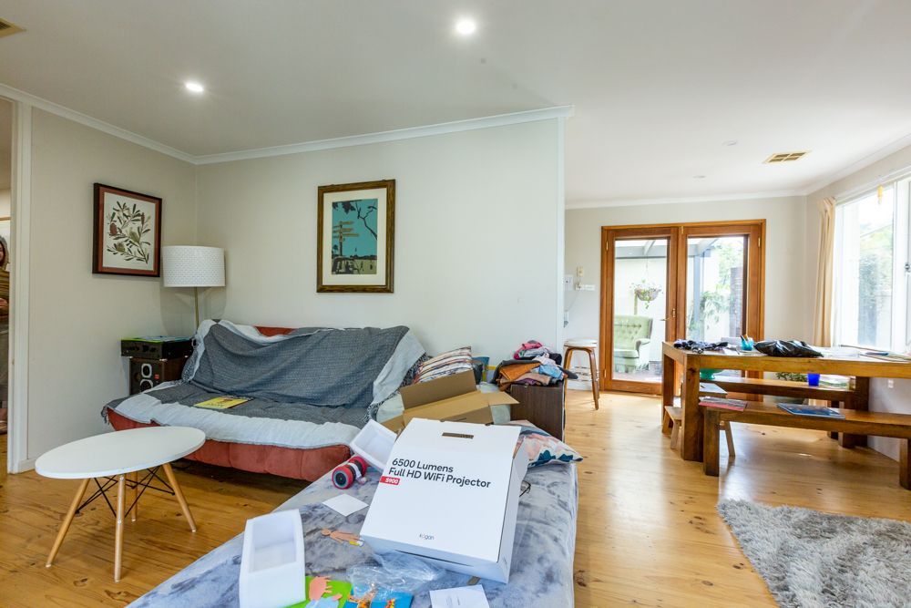 Interior entryway with open wooden door, tiled floor, carpeted living area, and a view of a tree outside.