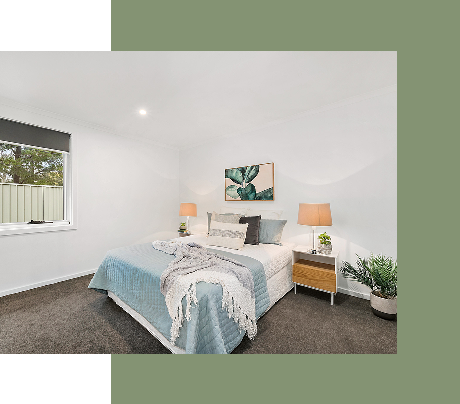 Bedroom with bed, lamps, and a painting, decorated with a light blue quilt and a potted plant.