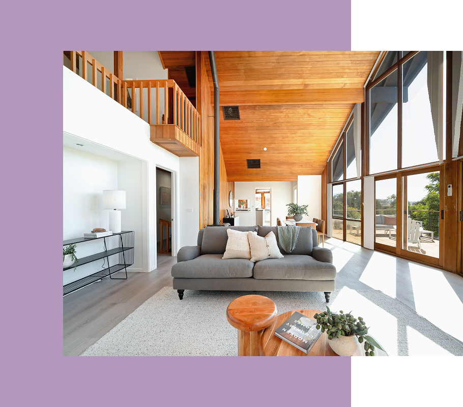 Living room with gray sofa, wooden ceiling, and large windows.